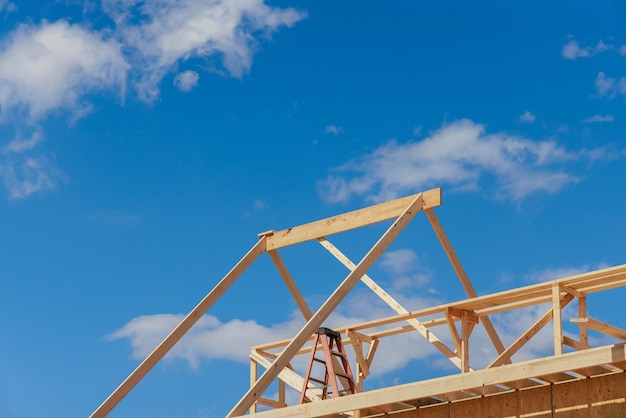 Wooden roof truss framing under construction in new home with a clear sky view