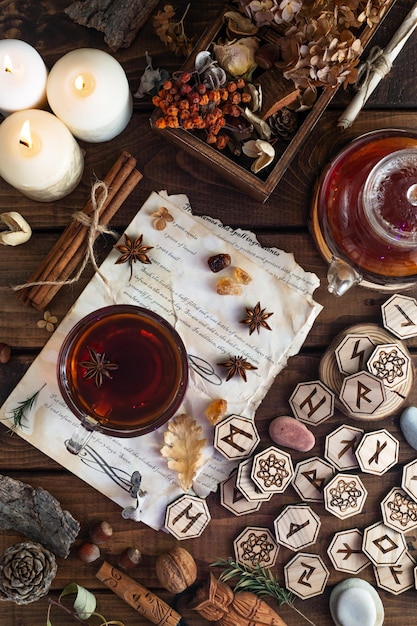 Wooden runes are lying on the table among the papers with notes. There is a mug of tea next to it. Astrology and esotericism.