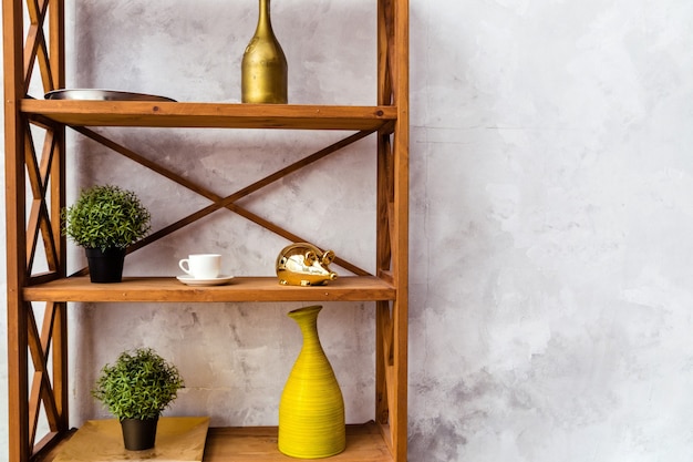 Wooden shelf with decorative elements and potted plants stands against a gray wall.  Horizontal photo