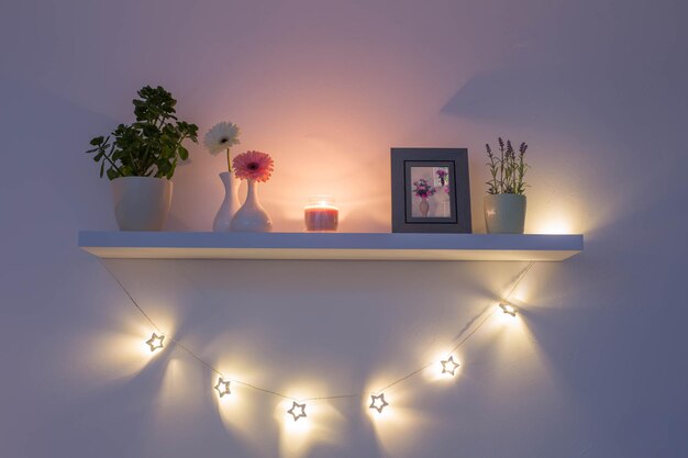 wooden shelf with flowers plants and frame on white wall