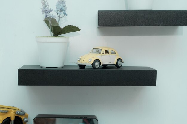 Wooden shelves with beautiful plants alarm clock toy cars and books on a light wall