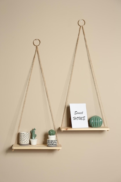 Wooden shelves with different decorative elements on beige wall