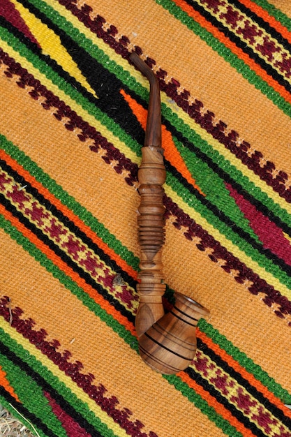 Wooden souvenir smoke pipe on the background of a woven hutsul carpet