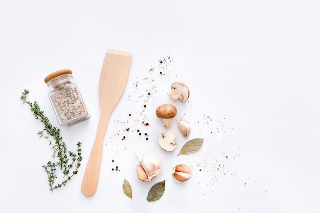 Wooden spatula with spices and vegetables on light grey background top view