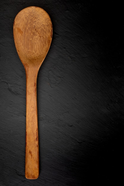 Wooden spoon on black slate with texture