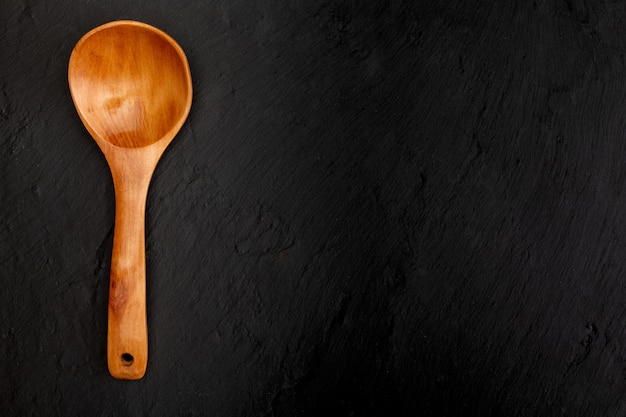 Wooden spoon on black slate with texture