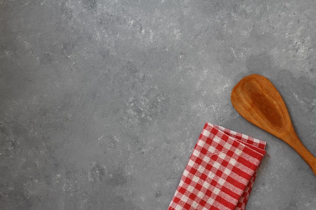 Wooden spoon and checkered tablecloth on stone background