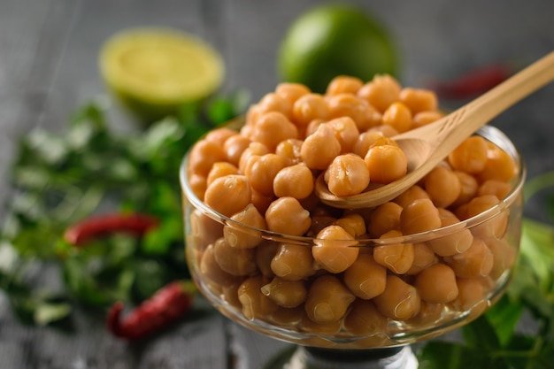 Wooden spoon in a glass bowl with boiled chickpeas with pepper and herbs