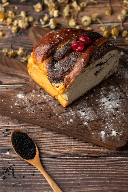 A wooden spoon of poppy seeds near freshly baked cake . 