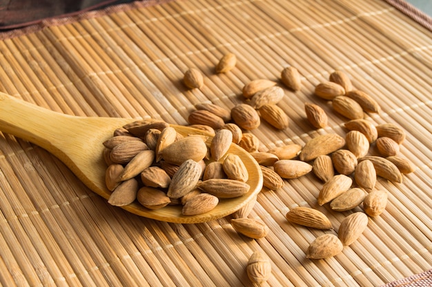 Wooden spoon with almonds on a bamboo napkin