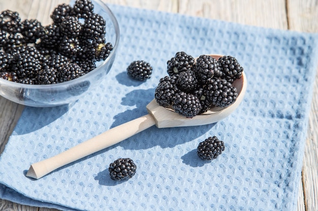 A wooden spoon with blackberries lies on a blue napkin Close up