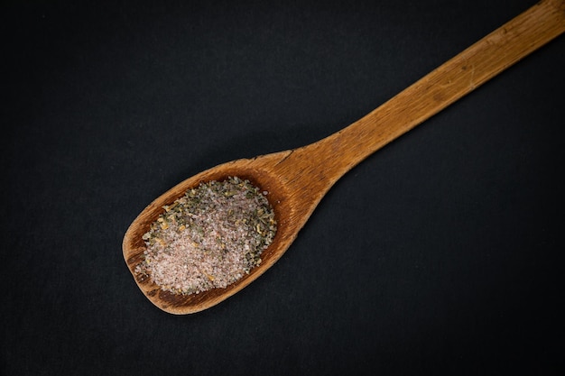 wooden spoon with salt and spices on a dark background