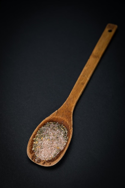 wooden spoon with salt and spices on a dark background