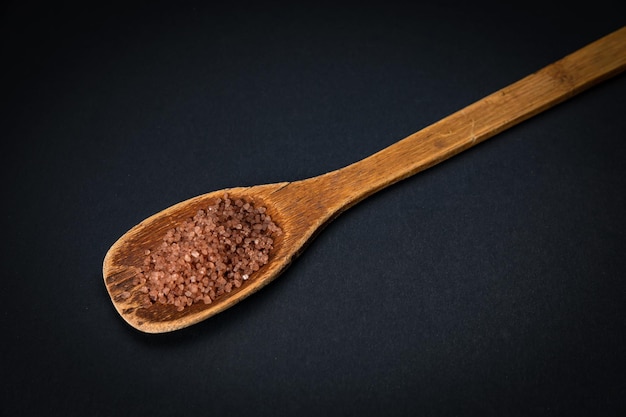 wooden spoon with salt and spices on a dark background