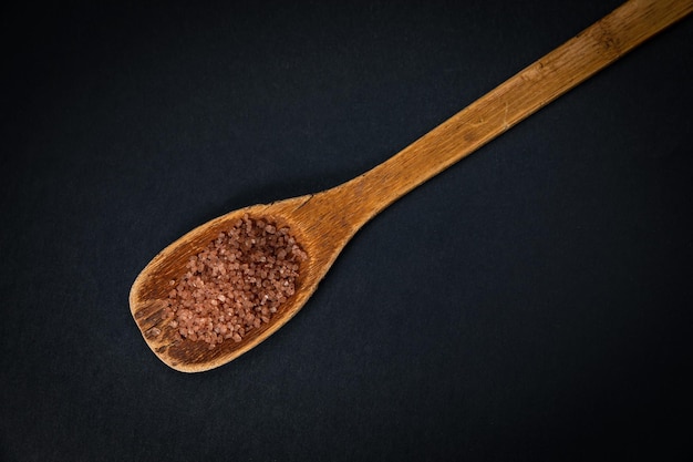 wooden spoon with salt and spices on a dark background