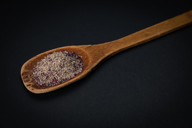 wooden spoon with salt and spices on a dark background