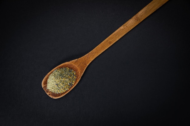 wooden spoon with salt and spices on a dark background