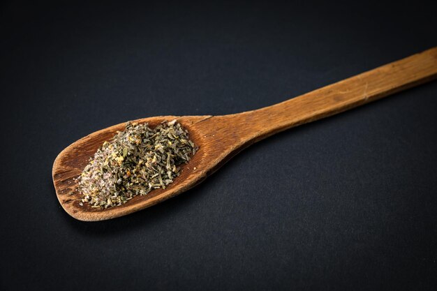 wooden spoon with salt and spices on a dark background