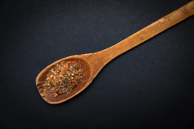 wooden spoon with salt and spices on a dark background