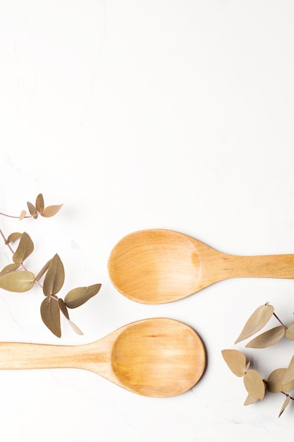 Wooden spoons and dry leaves on a marble background with copy space