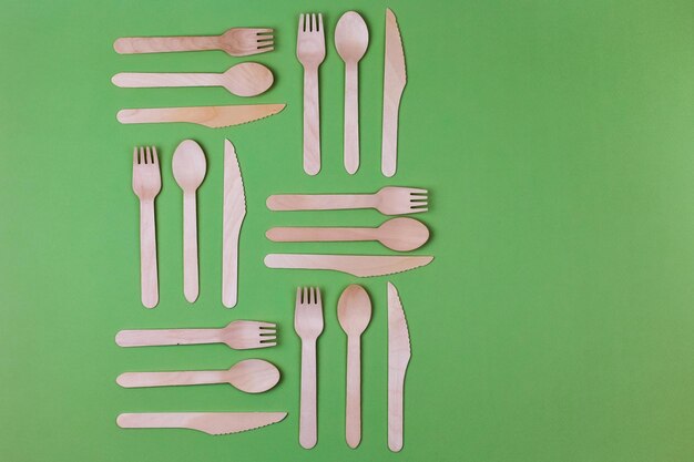 Wooden spoons forks knives on a green background Pattern Zero waste concept Place for an inscription