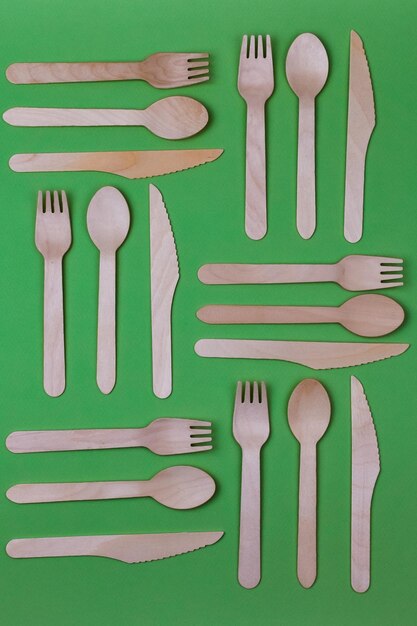 Wooden spoons forks knives on a green background Pattern Zero waste concept