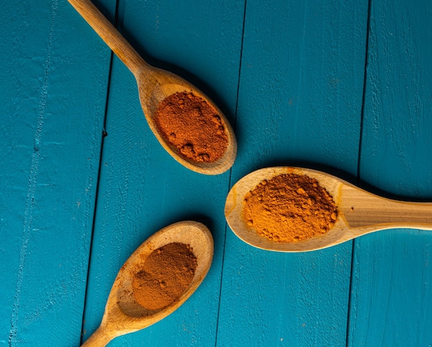 Wooden spoons with spices on a blue rustic wooden table