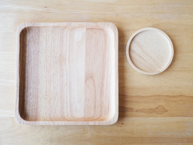 Wooden square and round plates on wood background