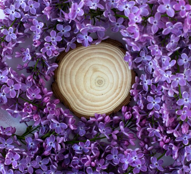 Wooden stand surrounded by lilacs Wooden round background