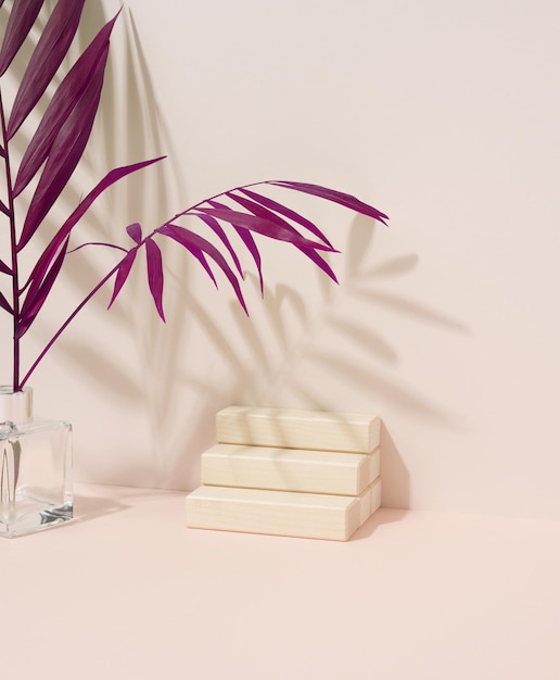 Wooden steps for the display of cosmetics and a purple palm leaf on a beige background