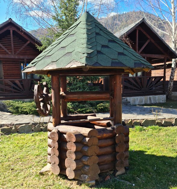 A wooden structure with a green roof sits in the grass.