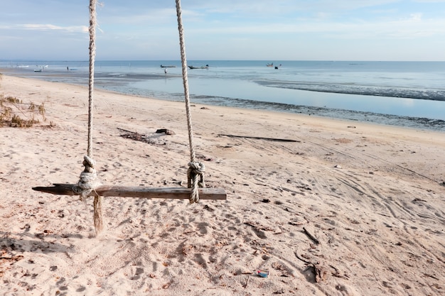 Wooden swing hanging on the beach. 