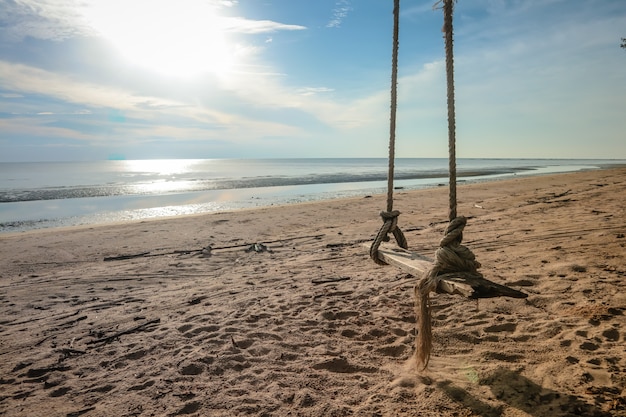 Wooden swing hanging on the beach. 