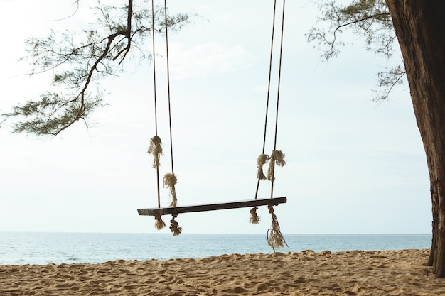 Photo wooden swing hanging on the tree on the beach