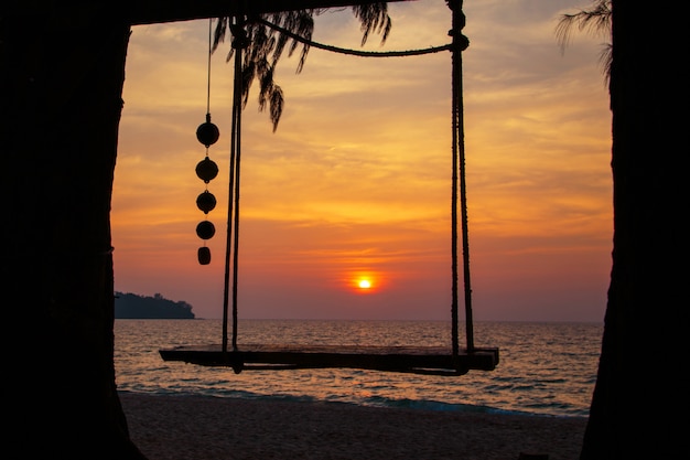 Wooden swing sunset on the sea beach