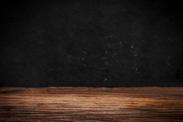 Wooden table on black wall in dark room background