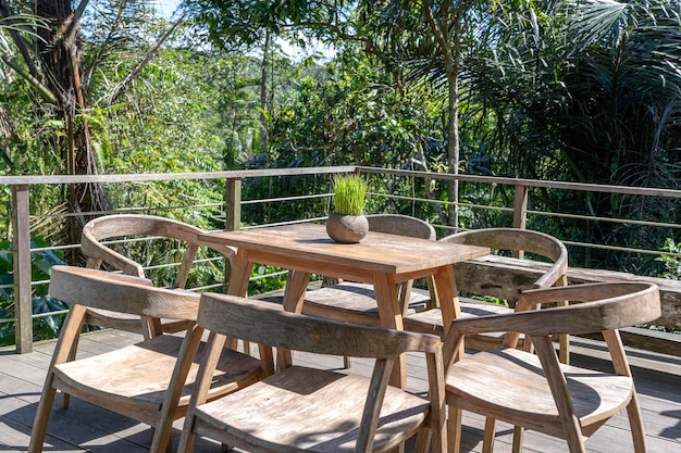 Wooden table and chairs in empty tropical cafe next to rice terraces in island Bali Indonesia close up