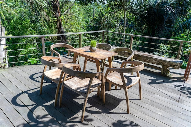 Wooden table and chairs in empty tropical cafe next to rice terraces in island Bali Indonesia