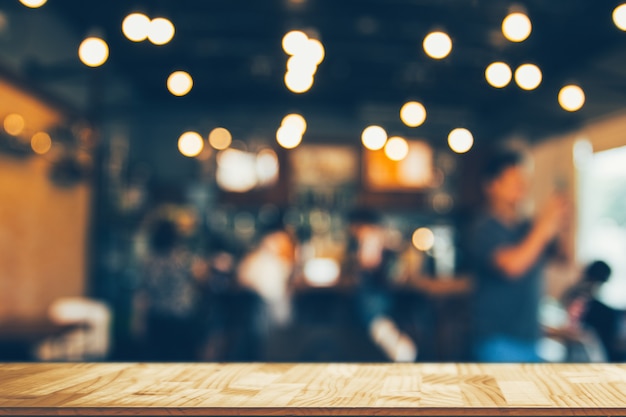 Wooden table in front of abstract blurred coffee shop lights backgroundÂ 