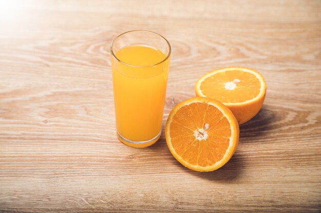 On a wooden table an orange and a glass with a drink