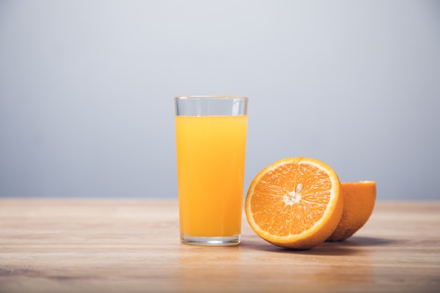 On a wooden table an orange and a glass with a drink