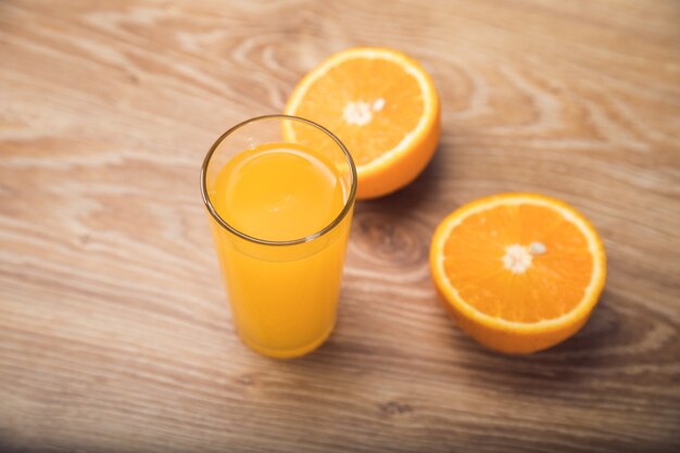 On a wooden table an orange and a glass with a drink