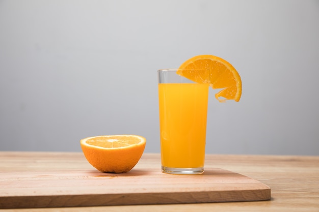 On a wooden table an orange and a glass with a drink