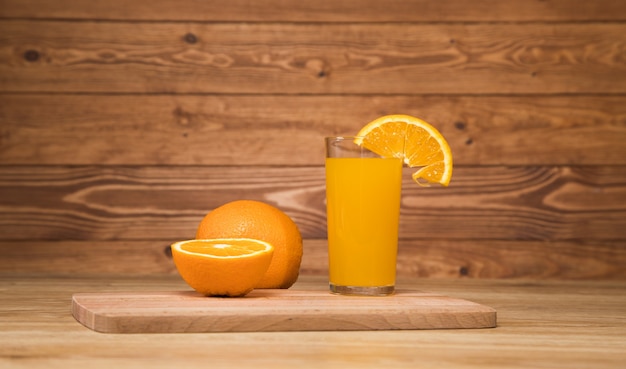 On a wooden table an orange and a glass with a drink