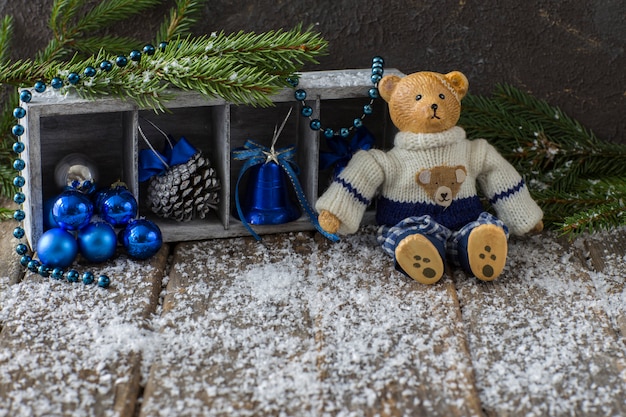 on the wooden table sits an old bear (toy) and winter decor