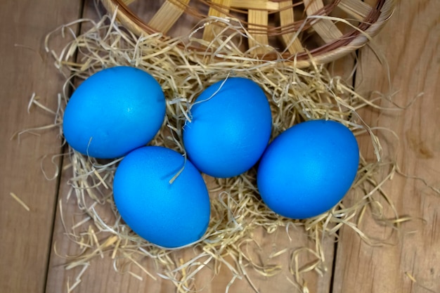 On a wooden table stained Easter eggs in a straw nest Easter and religion concept