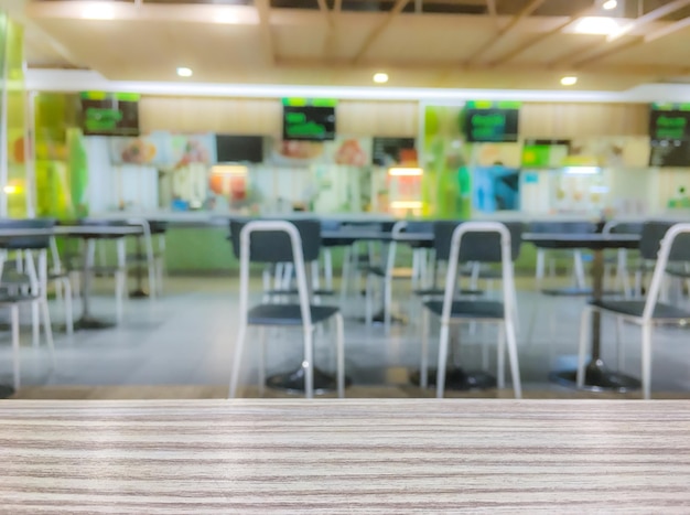 Wooden table top on blurred food court in shopping mall background