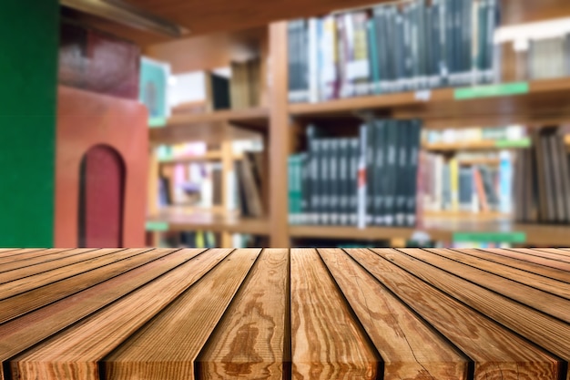 Wooden table top on blurred shelves book stacked in library