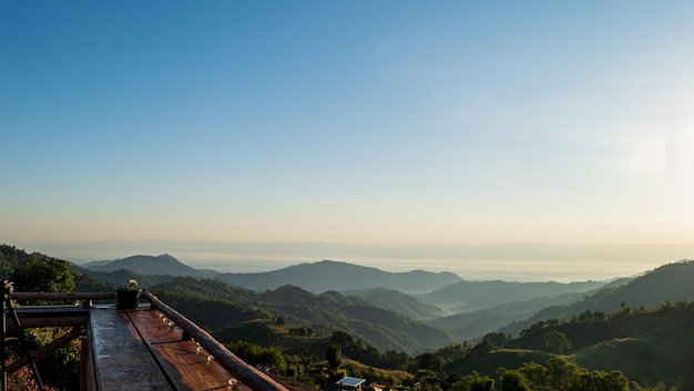 Wooden table top natural landscape of mountains and blue sky with sun light in the morning time