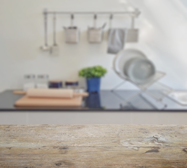 Wooden table top with blur of modern ceramic kitchenware and utensils on the countertop